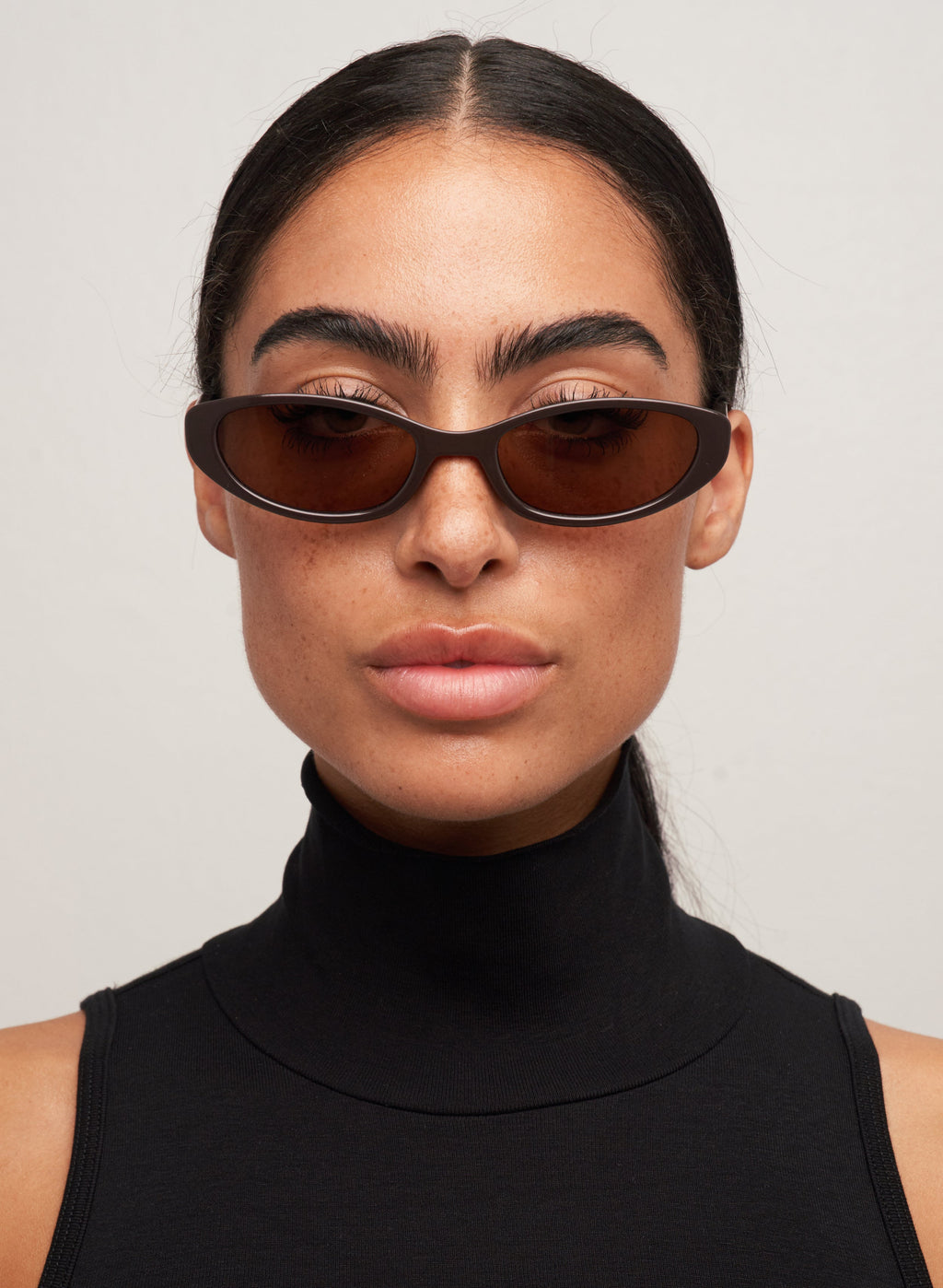 Otra Eyewear- Lulu Dark Chocolate- Front portrait view of a model wearing the Lulu cat-eye sunglasses in dark chocolate with brown lenses against a light background.